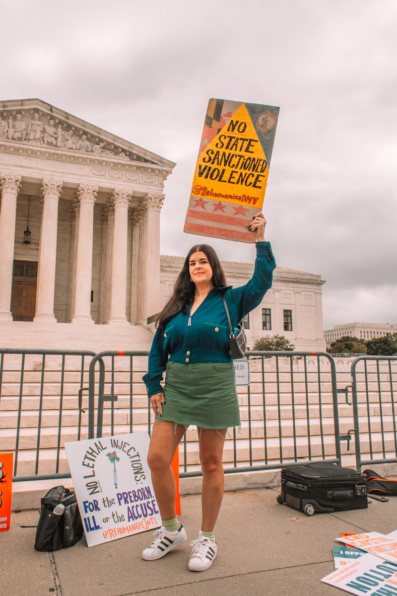 a woman holding a sign in front of the supreme building